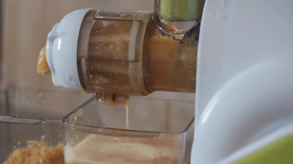 4K Closeup view auger juicer pressing homemade orange juice and pulp. Fresh healthy drink Vegan food