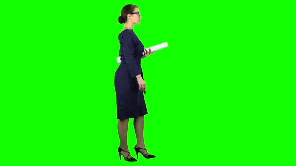 Designer Girl Comes with a Drawing in Her Hands. Green Screen. Side View