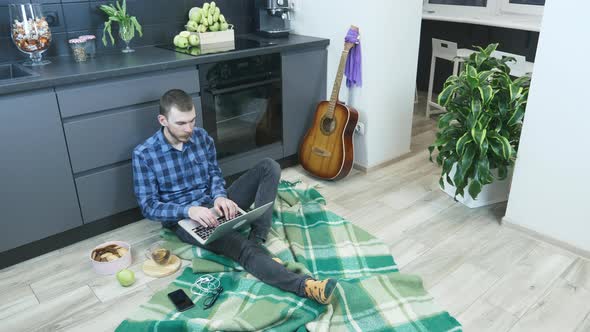 Young male freelancer typing on laptop computer & working from home workplace during self isolation