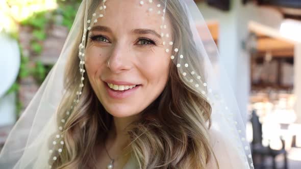 Happy Beautiful Bride with Long Wavy Hair Under the Veil