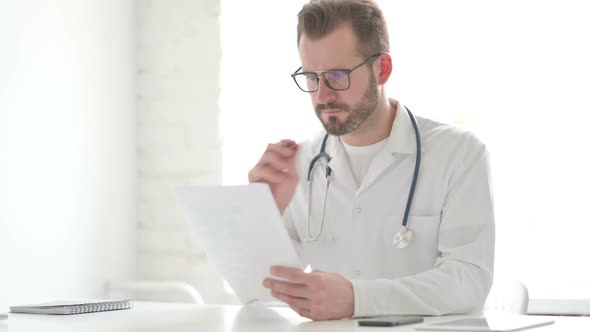 Doctor Reading Documents While Sitting in Office