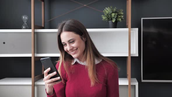 Well Dressed Excited Young Woman Checking Good News on Smart Phone at Modern Home in the Day