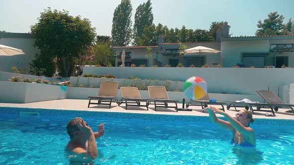 Man and Woman Playing Ball in Home Pool