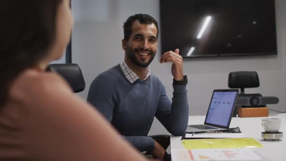 Middle eastern man smiling while looking at his female colleague in meeting room at office