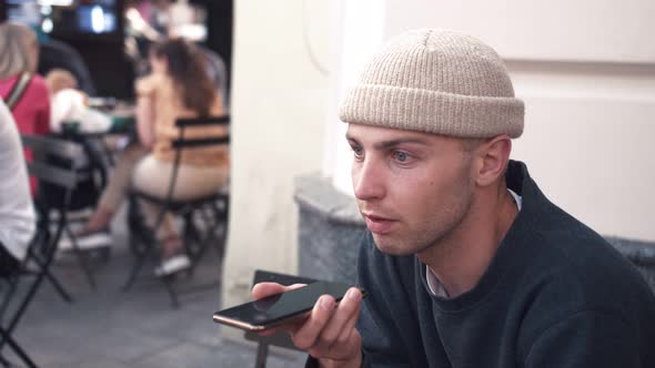 Young Caucasian Man Talking On Mobile Phone At Outdoor Cafe