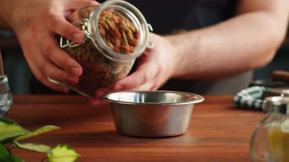 Putting Dried Dog Food in Metal Bowl Closeup Granules