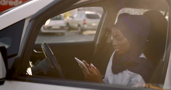 Black Muslim Woman Using Tablet in a White Car