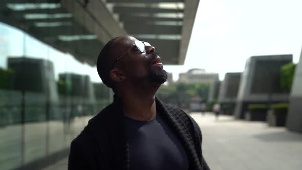 Portrait of an African-American Man Walking Down a City Street During the Day and Looking Around at