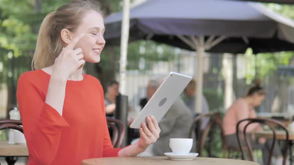 Online Video Chat on Tablet By Young Woman Sitting in Cafe Terrace