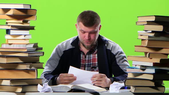 Man Sitting at His Desk Writes His Notebook Information. Green Screen