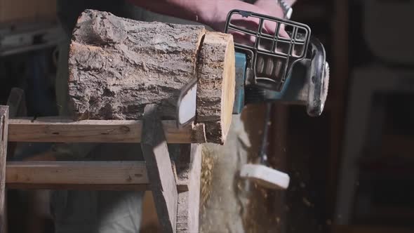 Man Is Sawing a Wood with an Electrical Chainsaw at Carpentry, Slow Motion