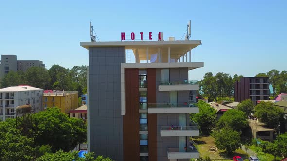 Drone flight around hotel in small town on seashore.