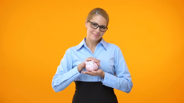 Female Bank Manager Holding Piggybank in Hand, Pension Fund, Deposit Insurance