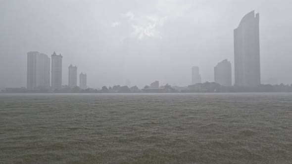 Heavy rain or rainstorm over Chao Phraya River in Bangkok with high buildings silhouette in backgrou