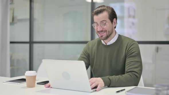 Young Businessman Talking on Video Call on Laptop in Office