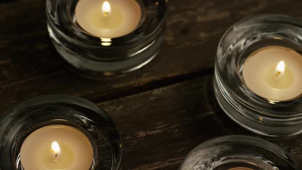 Tea candles with flaming wicks on a wooden background 