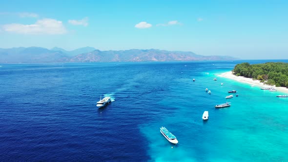 Cruise ships and other small boats sitting on the surface of crystal clear blue waters of a tropical