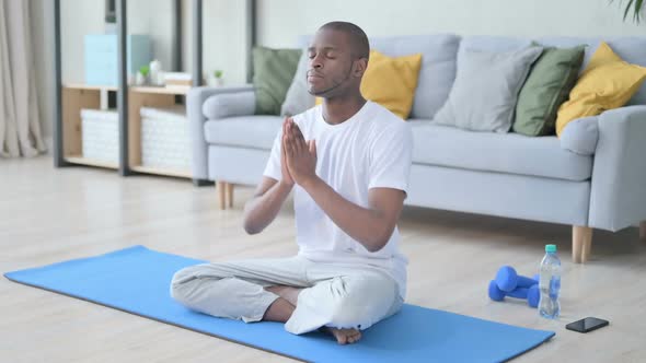 Young African Man Doing Stretches on Yoga Mat at Home