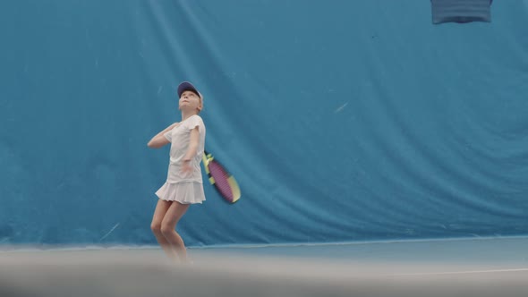 Young Girl Throwing And Hitting Tennis Ball