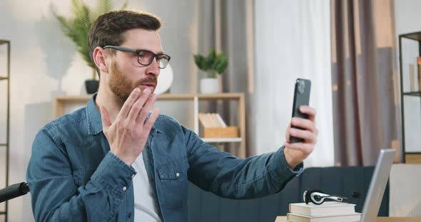 Man in Glasses Sitting in Wheelchair and Talking on Videocall Using Smartphone