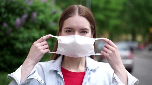 A young, attractive girl on the street puts on a protective mask