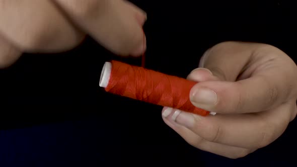 Winding Red sewing thread on spool with both hands