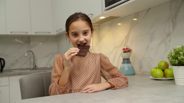 Beautiful Girl Eating Whole Bar of Chocolate Savoring Dessert at Home