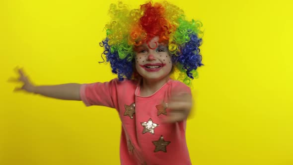 Little Child Girl Clown in Colorful Wig Waving Hands, Having Fun, Smiling. Halloween