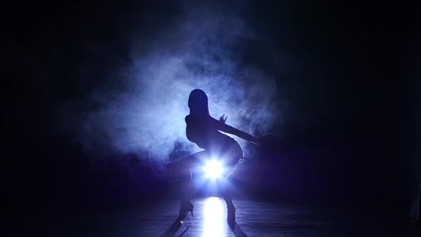 Woman Dancing Rumba in Studio, Silhouette. Dark Background, Blue Backlight