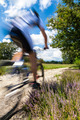 Cyclist in blurred motion riding on a rural road through green spring meadow  - PhotoDune Item for Sale