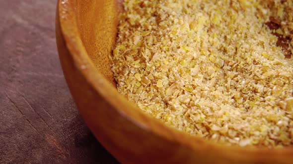 Crushed flax seeds in rustic wooden bowl. Macro. Rotation