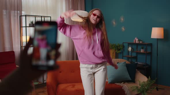 Joyful Blogger Teen Girl Dancing at Camera Filming Video Using Mobile Phone at Home in Living Room