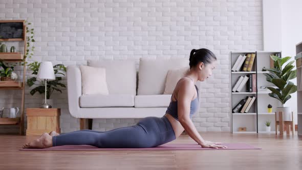 Asian woman practicing yoga pose Cobra at home.