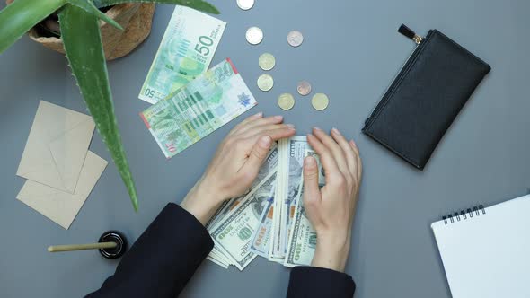 Hands rake up pile of US currency from table