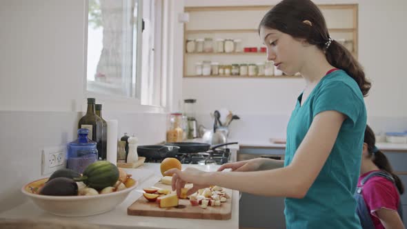 Teenage girl working cutting fruit for breakfast in the kitchen