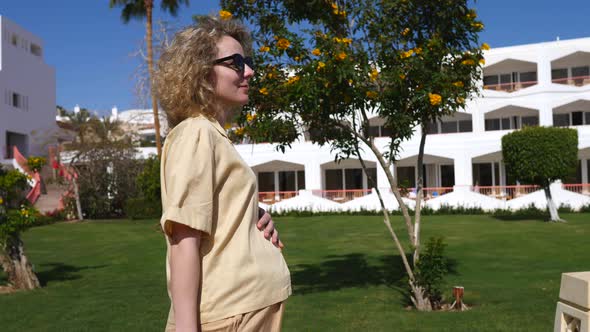 Pregnancy And Holidays Concept. Pregnant Woman Walking In Summer On Vacation In Hotel Resort.