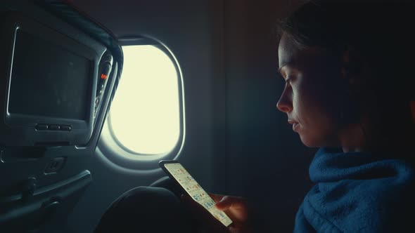 Young girl with a phone by the window 