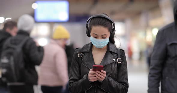 Chinese woman at train station in London wearing face mask to protect from sm