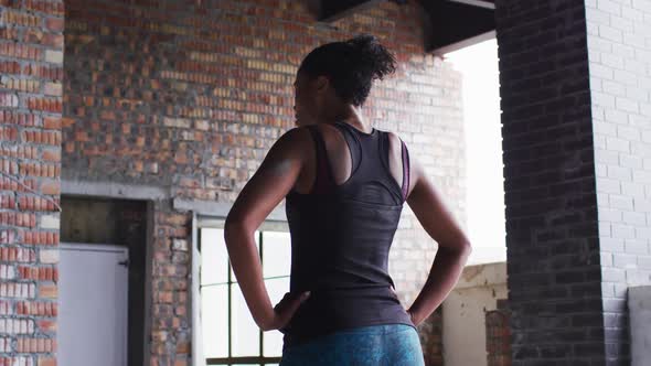 African american woman standing and resting after exercise in an empty urban building