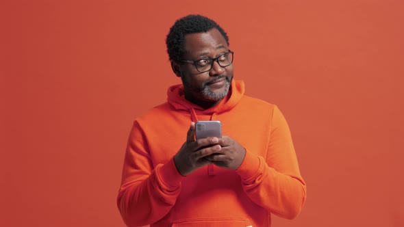 Smiling mature African man typing by phone