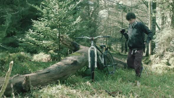 Young athletic teen grabs bike and sets off cycling within forest
