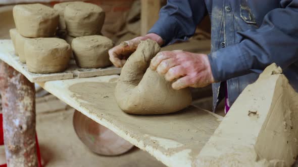 Hand pressing potters clay on grungy messy bench