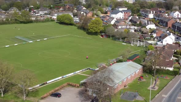 Aerial drone shot panning over village football pitch and housing estate, England