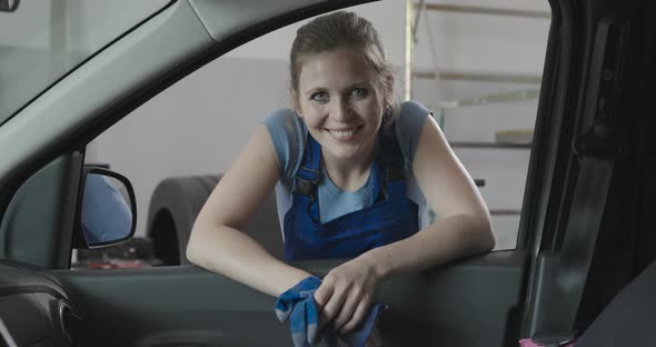 Smiling female mechanic leaning on a car window