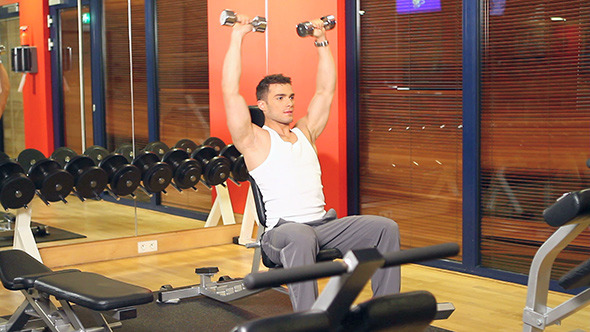 Muscular Man Doing Exercises With Dumbbells