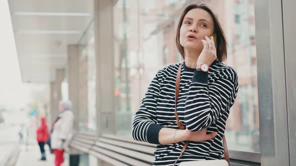 A Young Adult Woman Talking on the Phone While Waiting for the Bus