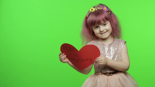 Child Girl Princess Holds Red Paper Heart with Text About Mother. Mother's Day