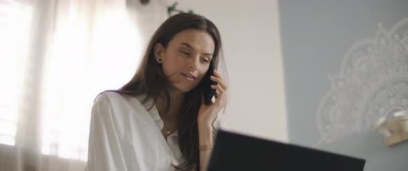 Close up of a woman in white shirt talking to someone on the phone, 