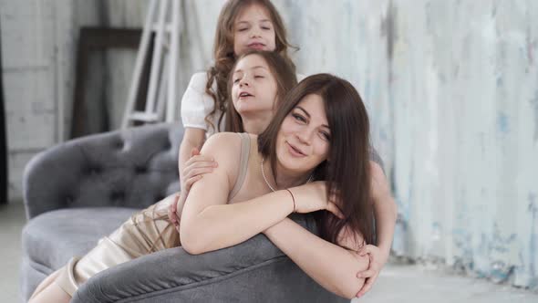 Mom Lies on the Couch and Cuddles with Her Daughters