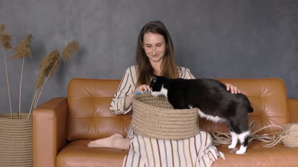 Woman Knitting at Home with her Cute Cat, handcrafting Home Baskets with Rope, Indoor, Copy Space